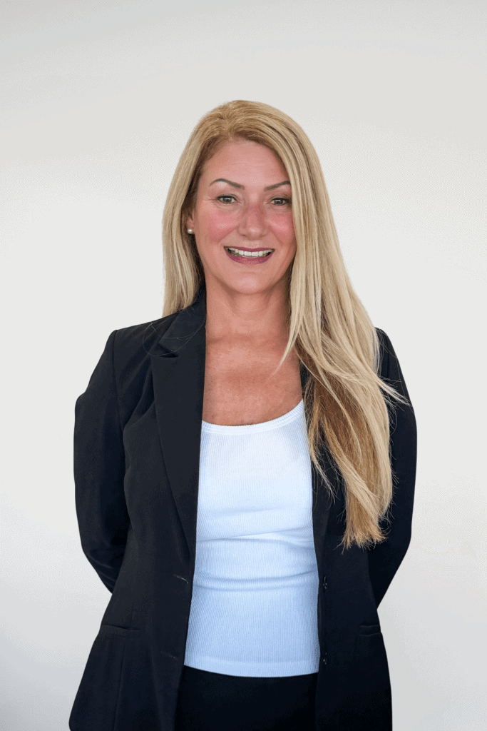 Confident woman with long blonde hair wearing a black blazer and white top, representing professionalism and trust in New Choice Homes' real estate services.